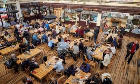 Ylhäältä kuvattu vilkas kauppahallin ruokailualue pöytineen